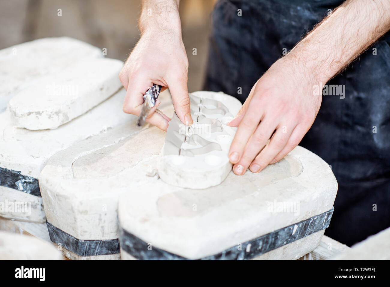 Lavoratore di sesso maschile di ottenere prodotti di argilla dalle forme di gesso alla fabbricazione ceramica, vista da vicino Foto Stock