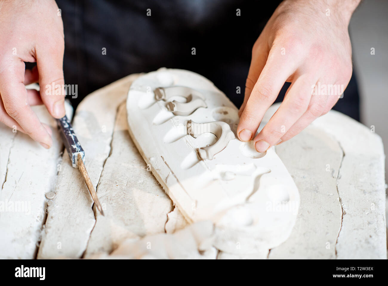 Lavoratore di sesso maschile di ottenere prodotti di argilla dalle forme di gesso alla fabbricazione ceramica, vista da vicino Foto Stock