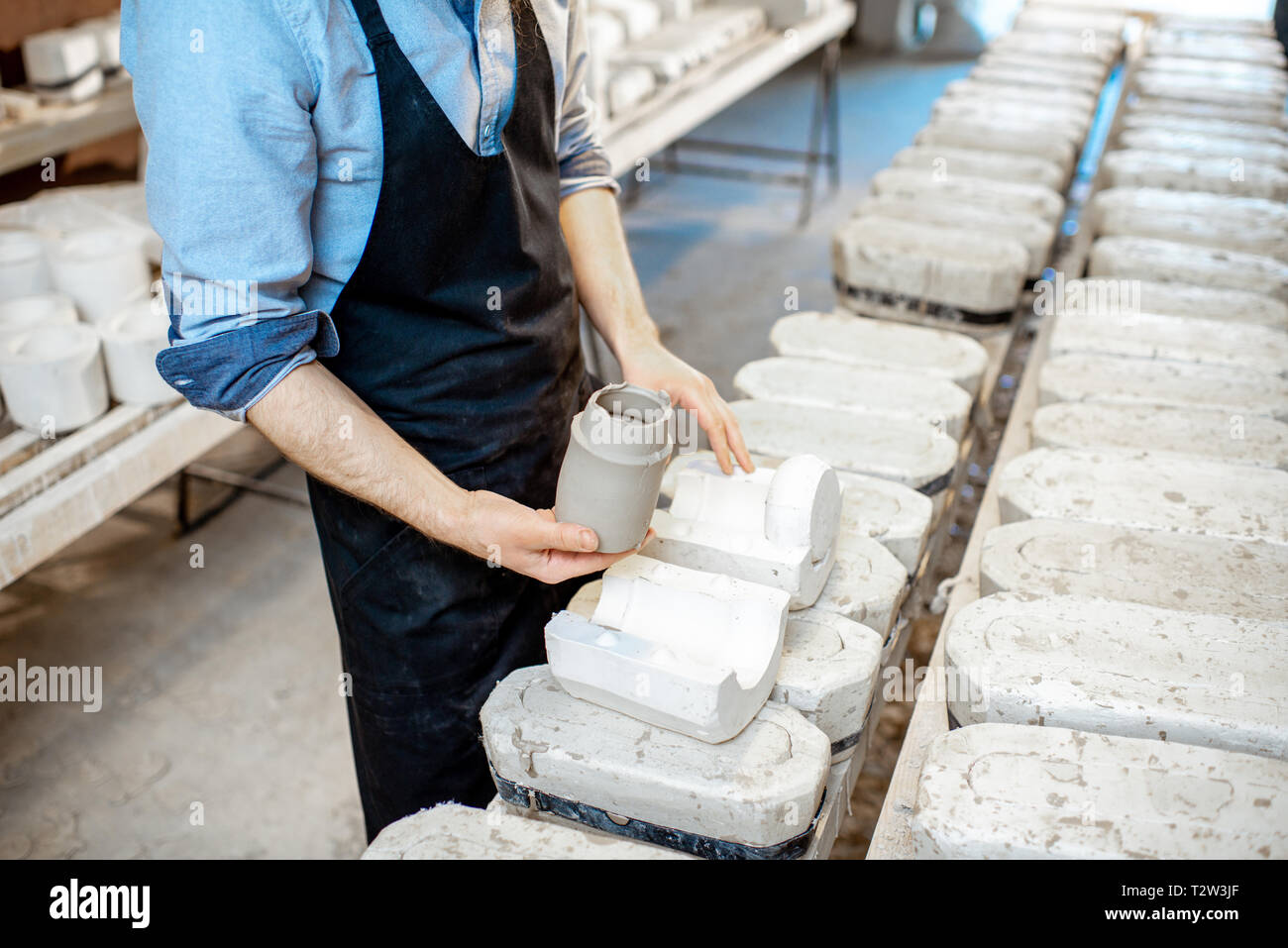 Lavoratore di sesso maschile di ottenere prodotti di argilla dalle forme di gesso alla fabbricazione ceramica, vista da vicino Foto Stock