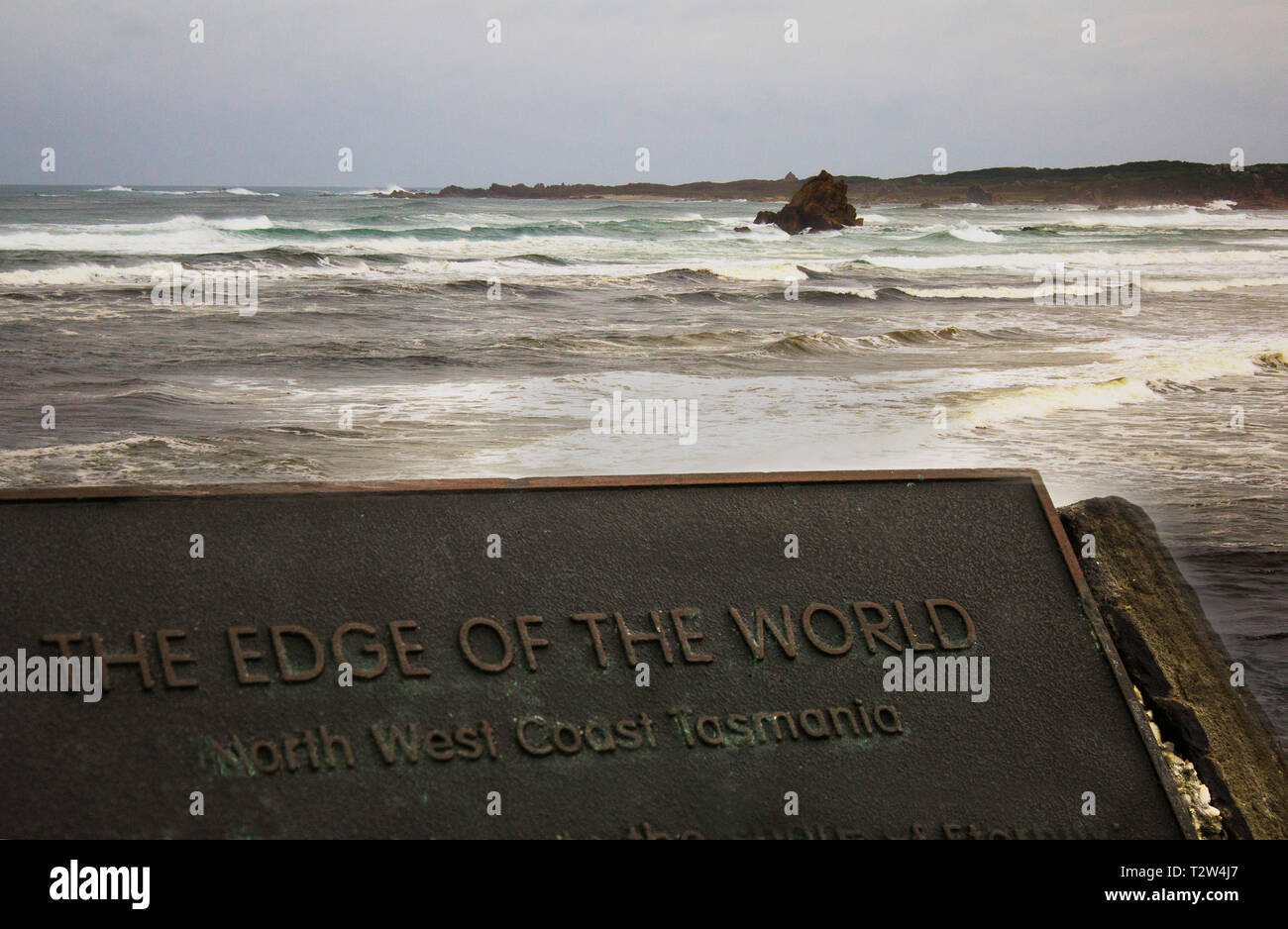 Un segno dichiara il bordo del mondo presso la regione conosciuta come questo nel nord-ovest della Tasmania, con scabra oceano e cielo nuvoloso in background Foto Stock