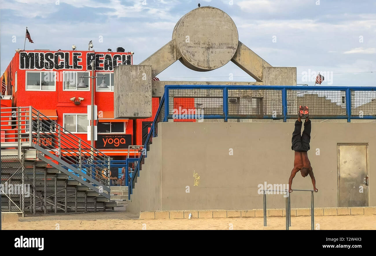 LOS ANGELES, CALIFORNIA, STATI UNITI D'America - 25 agosto 2015: un bodybuilder esegue un handstand sulle barre parallele a Venice Beach in California. Foto Stock