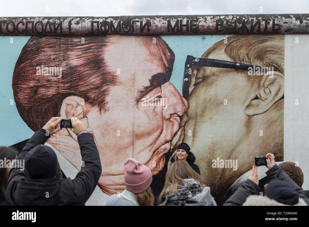 I turisti al 'My Dio aiutami a sopravvivere a questo amore letale' (o 'bacio fraterno") pittura murale di Dmitri Vrubel presso la East Side Gallery di Berlino. Foto Stock