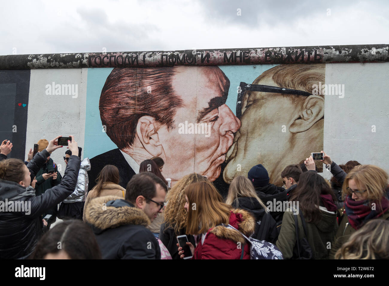 I turisti al 'My Dio aiutami a sopravvivere a questo amore letale' (o 'bacio fraterno") pittura murale di Dmitri Vrubel presso la East Side Gallery di Berlino Foto Stock