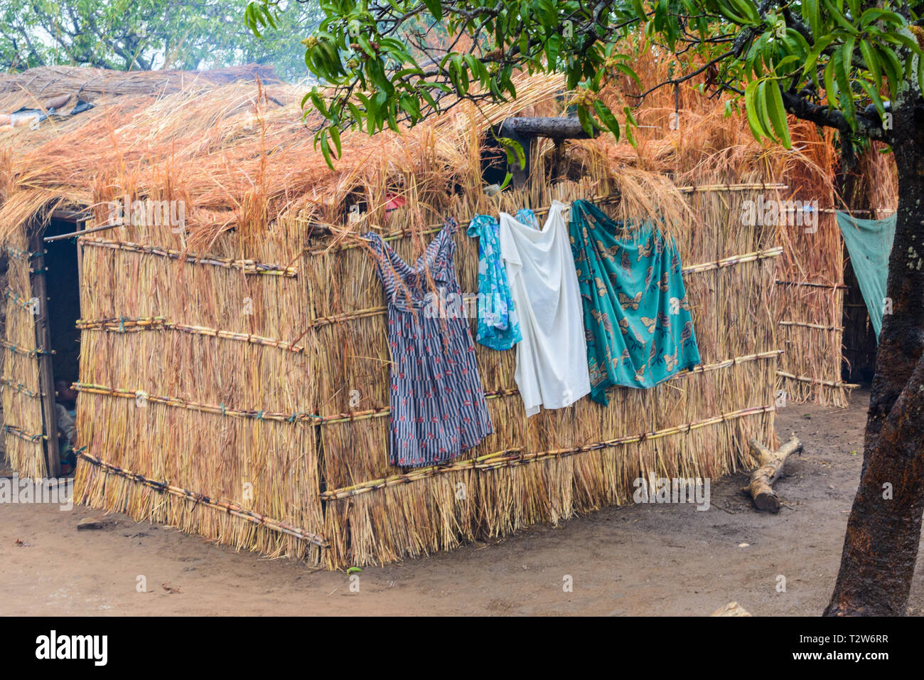 Womens vestiti appesi ad asciugare sul lato della parete di erba e edificio coperto nel villaggio del Malawi Foto Stock