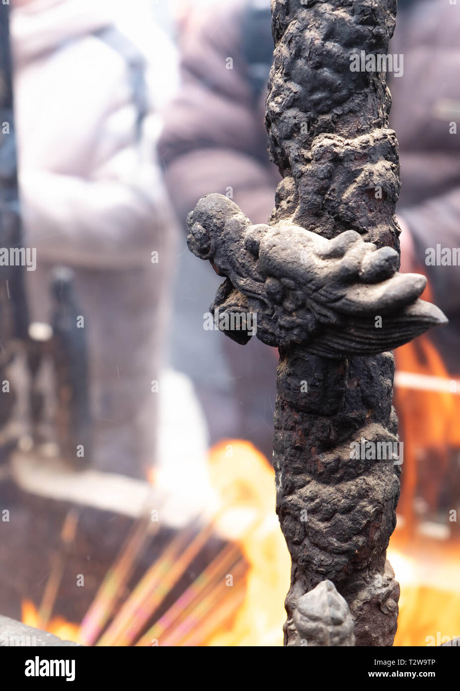 Close up di un altare con dragon carving, incenso bruciatore, joss pot, bastoncini di incenso bruciare con i fumi in un tempio buddista Foto Stock