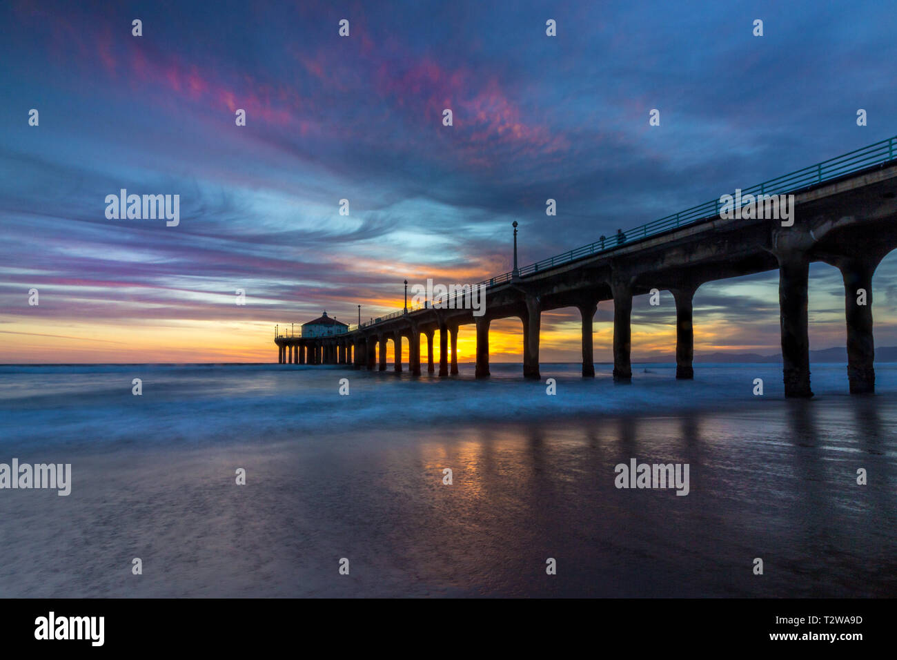 Lunga esposizione shot colorata del Cielo e nubi su Manhattan Beach Pier al tramonto con regolare lavaggio onde sulla spiaggia, Manhattan Beach, Californi Foto Stock