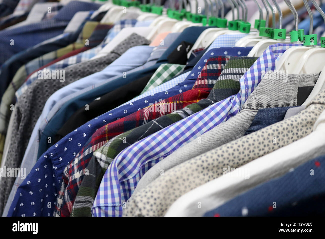 Eleganti camicie su appendiabiti in negozio sfocata. Alla vigilia del Venerdì nero. Sfondo per il design di un department store. Foto Stock