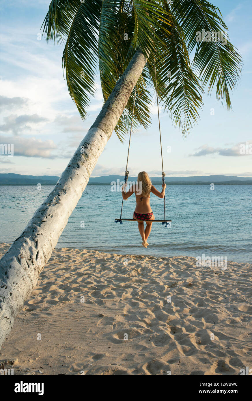 Vista posteriore della donna in una spiaggia swing attaccato a un albero di palma in isole San Blas. Destinazione di viaggio, stile di vita / Concetto di vacanza. Panama, Ott 2018 Foto Stock