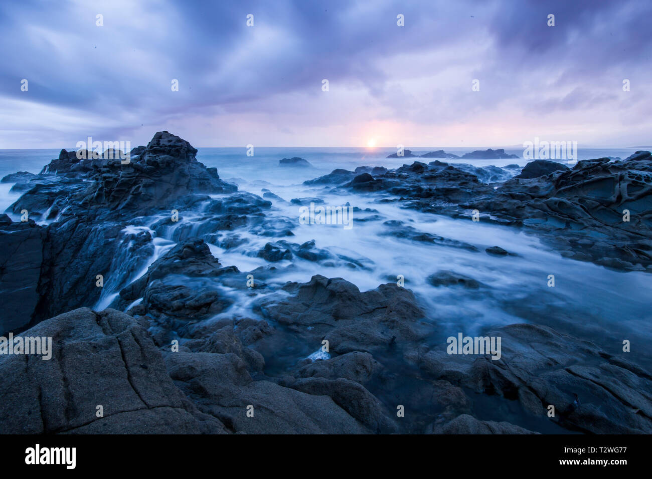 Una lunga esposizione delle onde di marea e laminazione su la costa rocciosa di Cambria California Foto Stock
