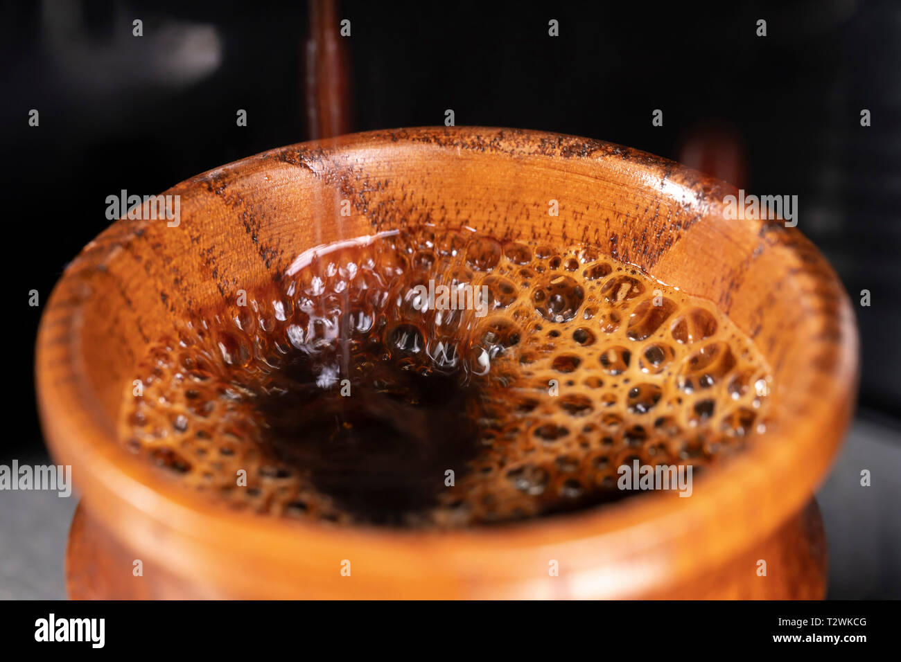 Il caffè viene preparato in una piccola tazza di legno da una macchina per il caffè. Foto Stock