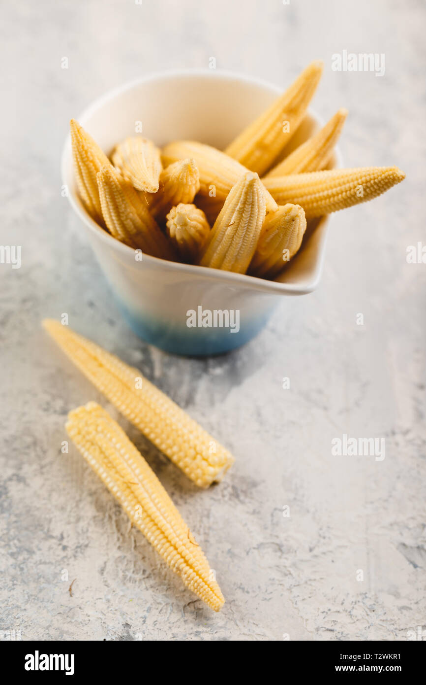 Fresca giovani baby corn sul cemento grigio sfondo Foto Stock