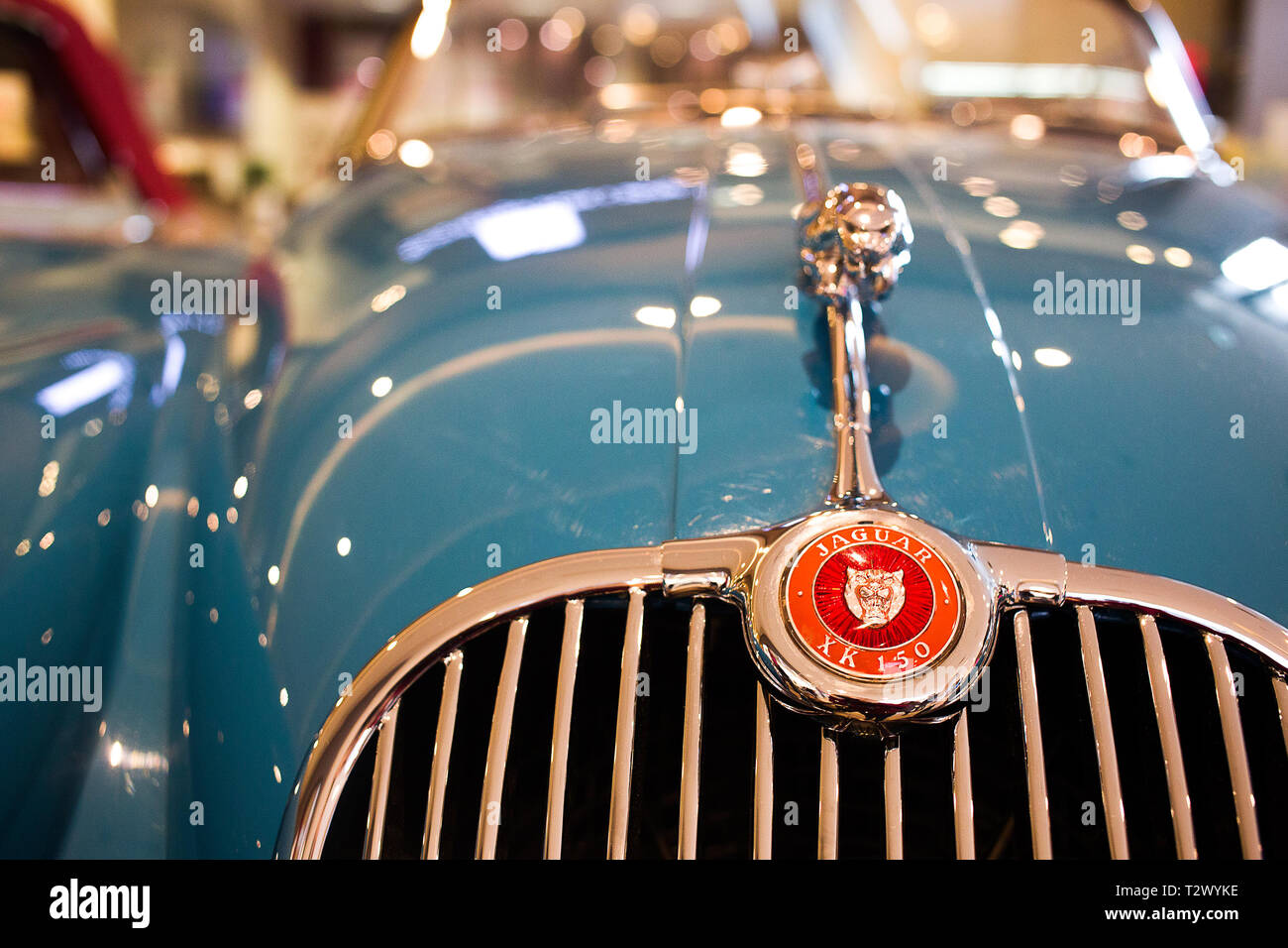 Poznan - Polonia / 28 Marzo 2019, parte anteriore del classico blu Jaguar XK150 con luci a soffitto riflessione sulla carrozzeria lucido e in piedi fuori logo rosso Foto Stock