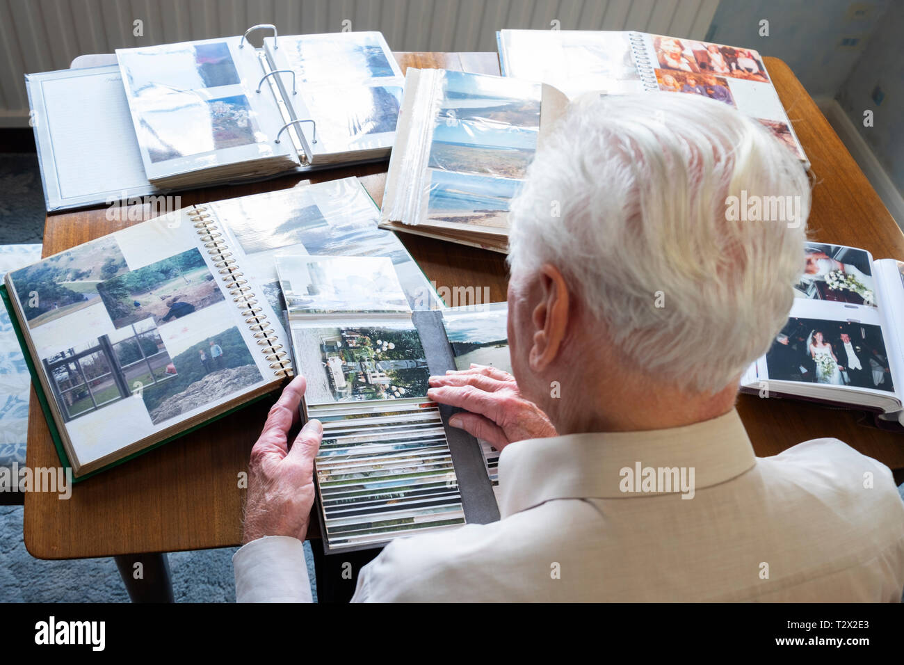 Vista dall'alto di un anziano uomo cerca attraverso il vecchio album di foto Foto Stock