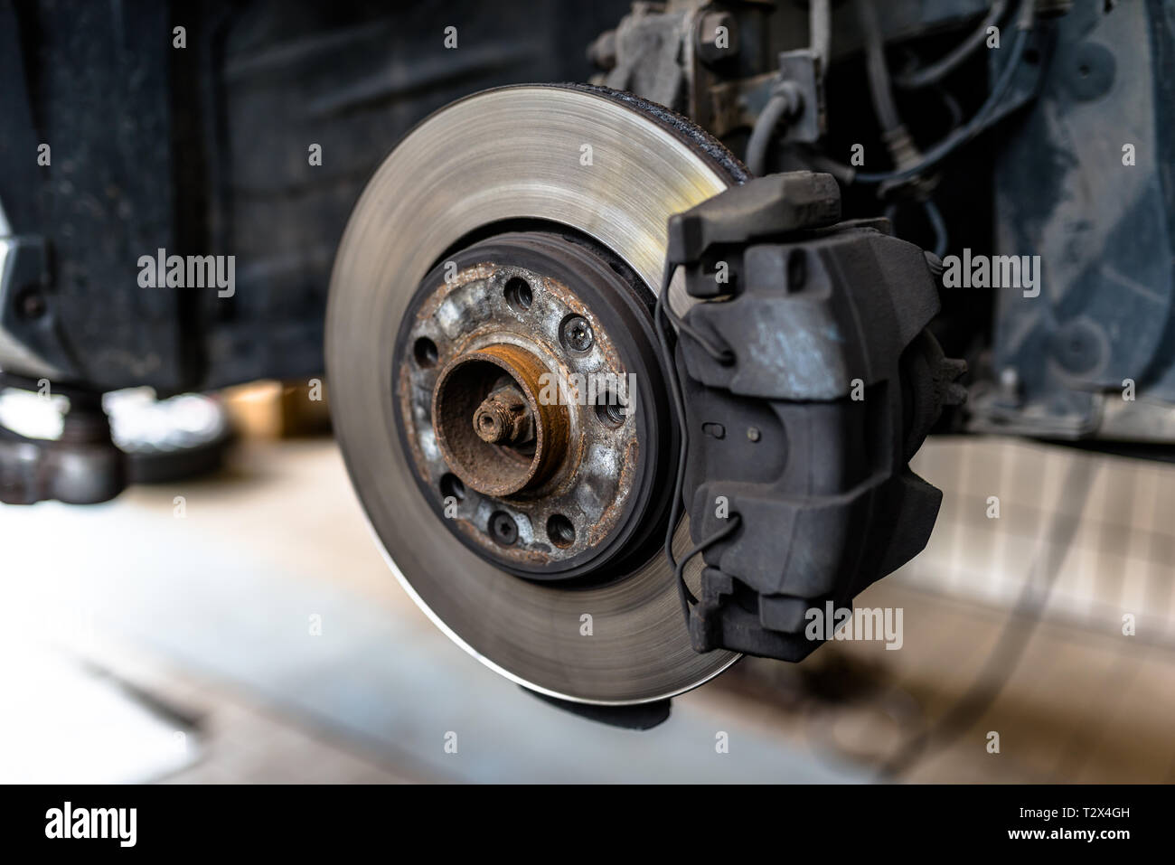 I dischi dei freni anteriori con la pinza e le pastiglie del freno in auto,  in un ascensore per auto in un'officina Foto stock - Alamy