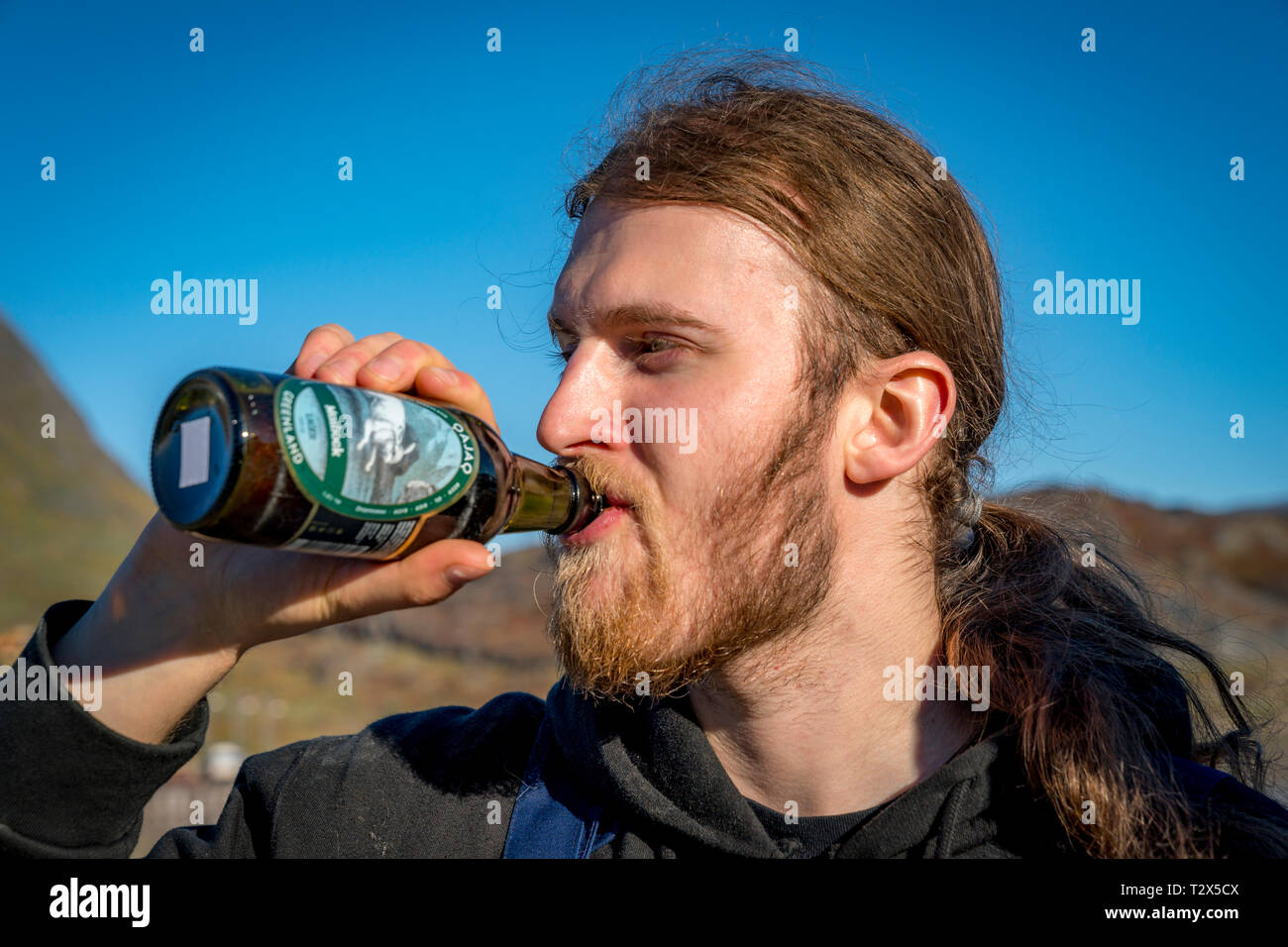 Maschio di bere una birra lager-Qajag, una birra prodotta a Narsaq in Groenlandia. Foto Stock