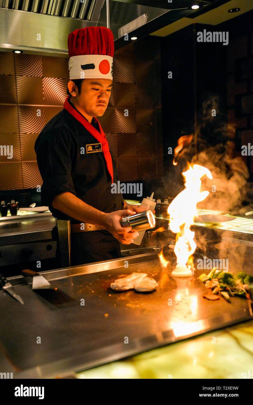 Lo chef giapponese per la cottura con il fuoco su una griglia a un giapponese steak house restaurant. Foto Stock