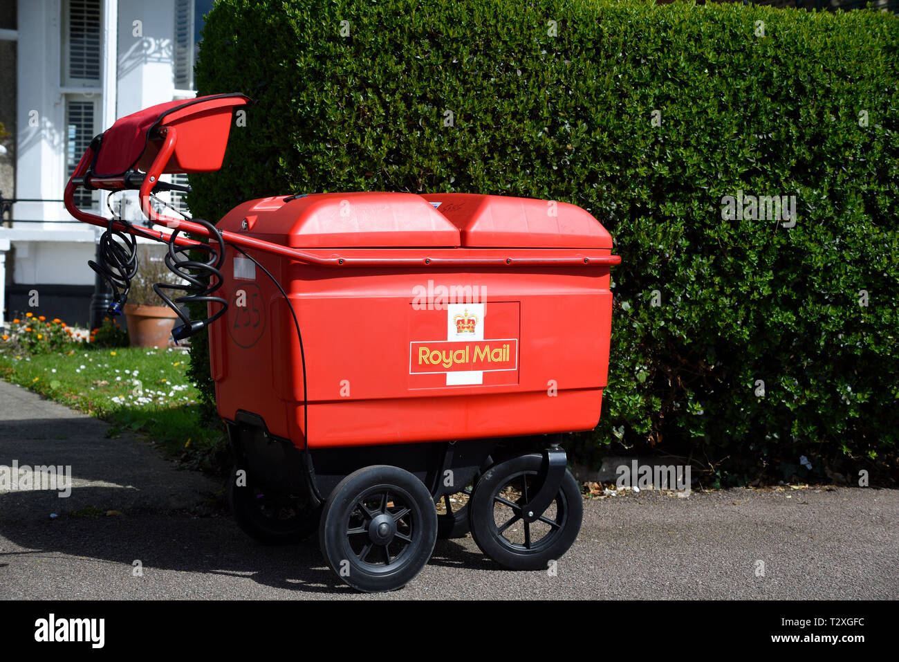 Royal Mail delivery carrello a sinistra in strada fuori casa di privet hedge. Post contenitore portante su ruote per il trasporto di lettere e pacchi. Carrello a mano Foto Stock
