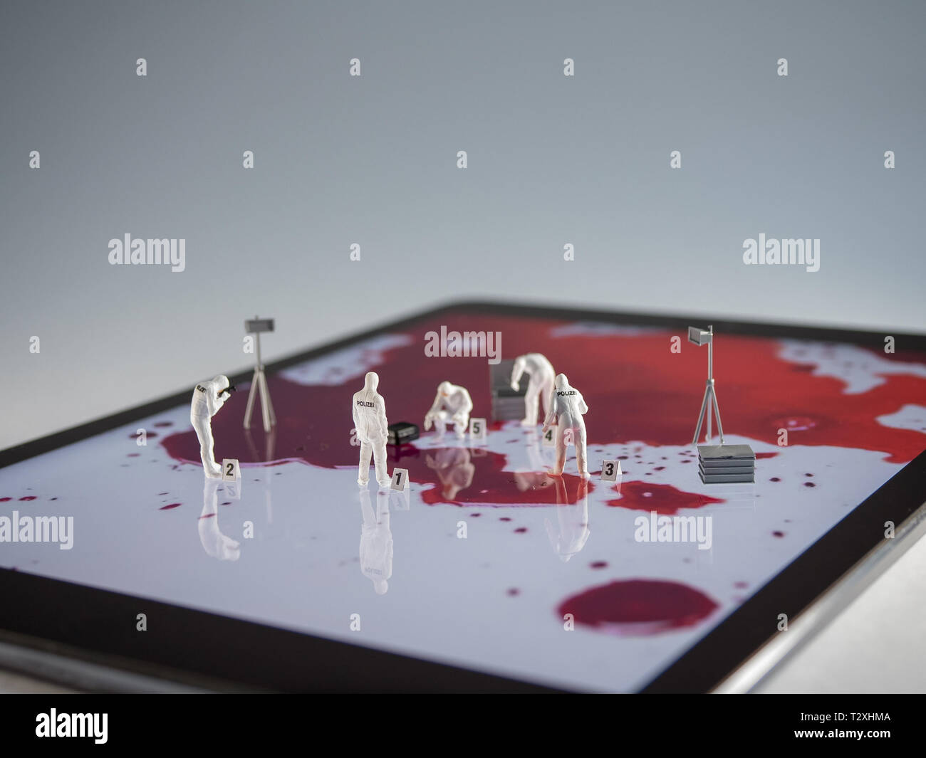 Forensics alla scena del crimine con persone in miniatura sul tablet pc Foto Stock