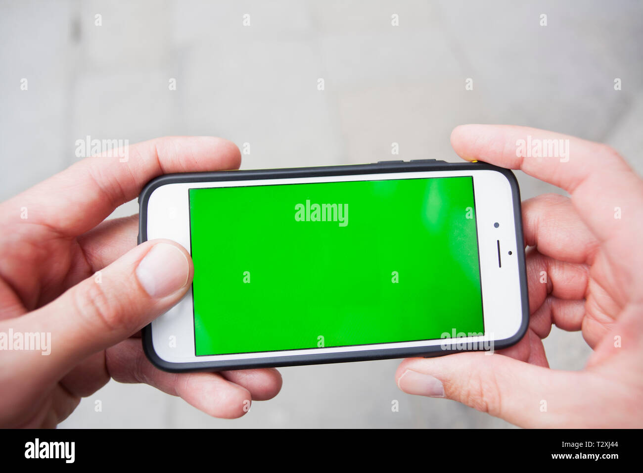 Punto di vista personale di un uomo utilizzando uno smartphone con schermo verde Foto Stock