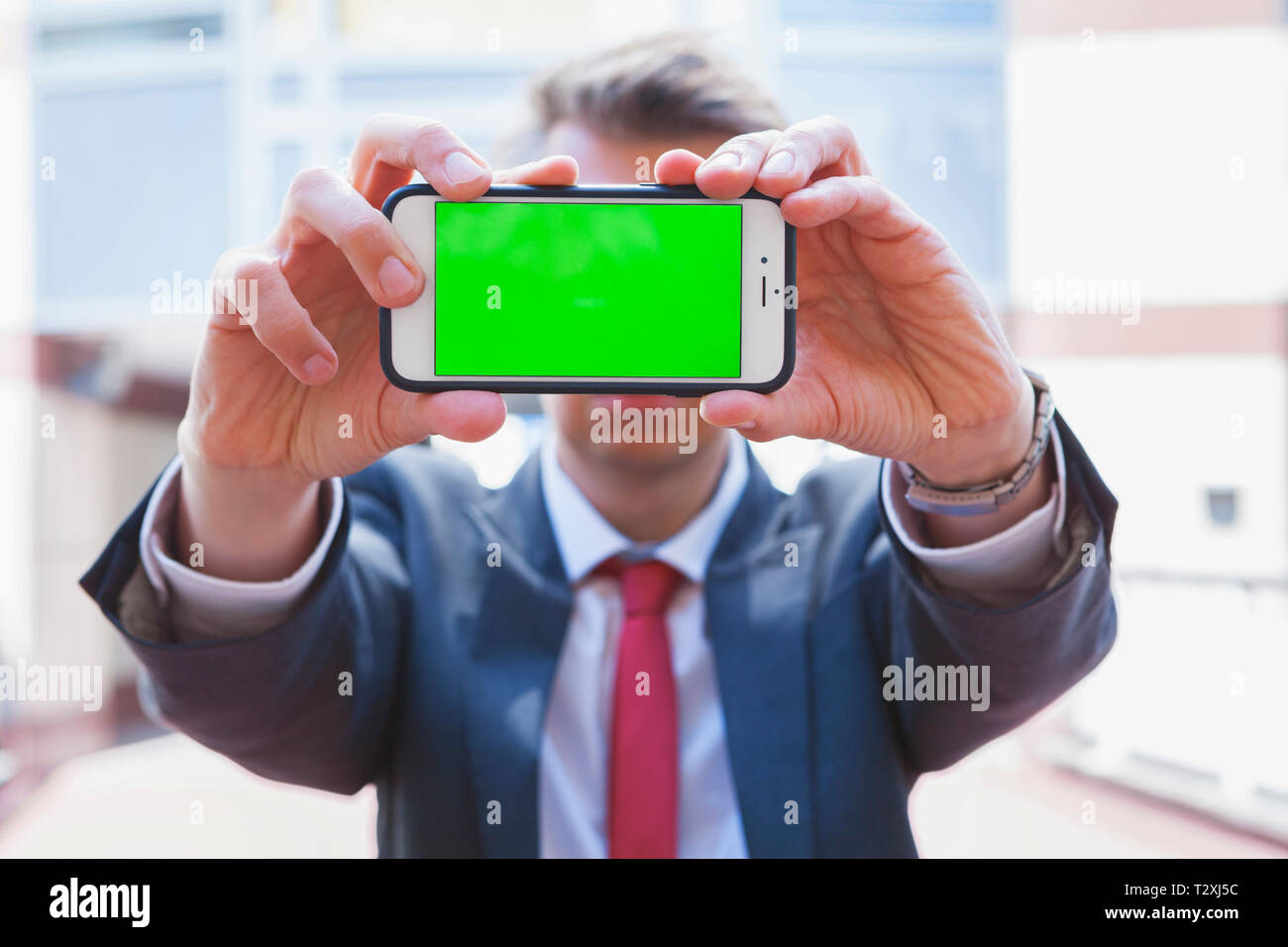Imprenditore tenendo uno smartphone con schermo verde Foto Stock