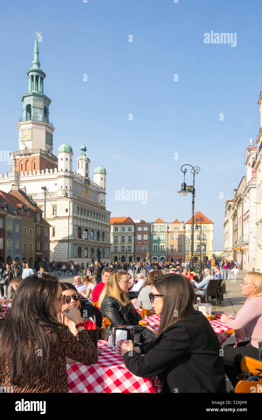 Persone uomini e donne seduti fuori a mangiare e a bere al caffè nel caldo sole primaverile in piazza della città vecchia nella città polacca di Poznan in Polonia Foto Stock