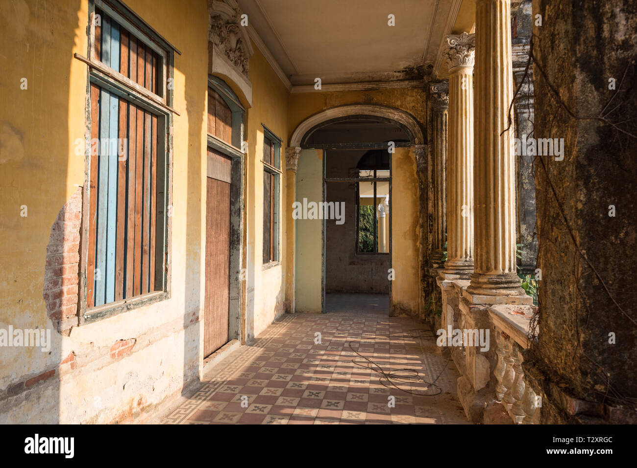 Passaggio con pavimento piastrellato e saliti a bordo delle finestre lungo le colonne al secondo piano del Palazzo o Villa Bodega. Foto Stock