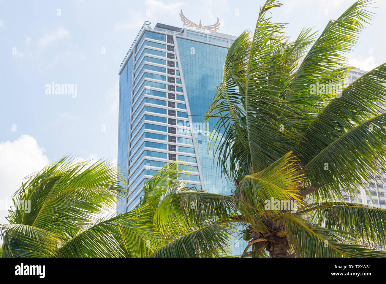 Da Nang, Vietnam - 1 Novembre 2018: Muong Thanh Luxury Da Nang, un hotel fronte spiaggia a 4 stelle e alberi di noce di cocco contro il cielo blu. Foto Stock