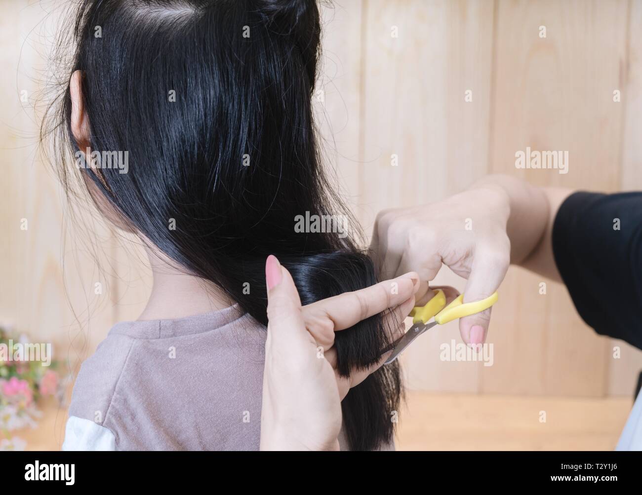 Ragazza giovane ottiene un taglio di capelli da sua madre. Foto Stock