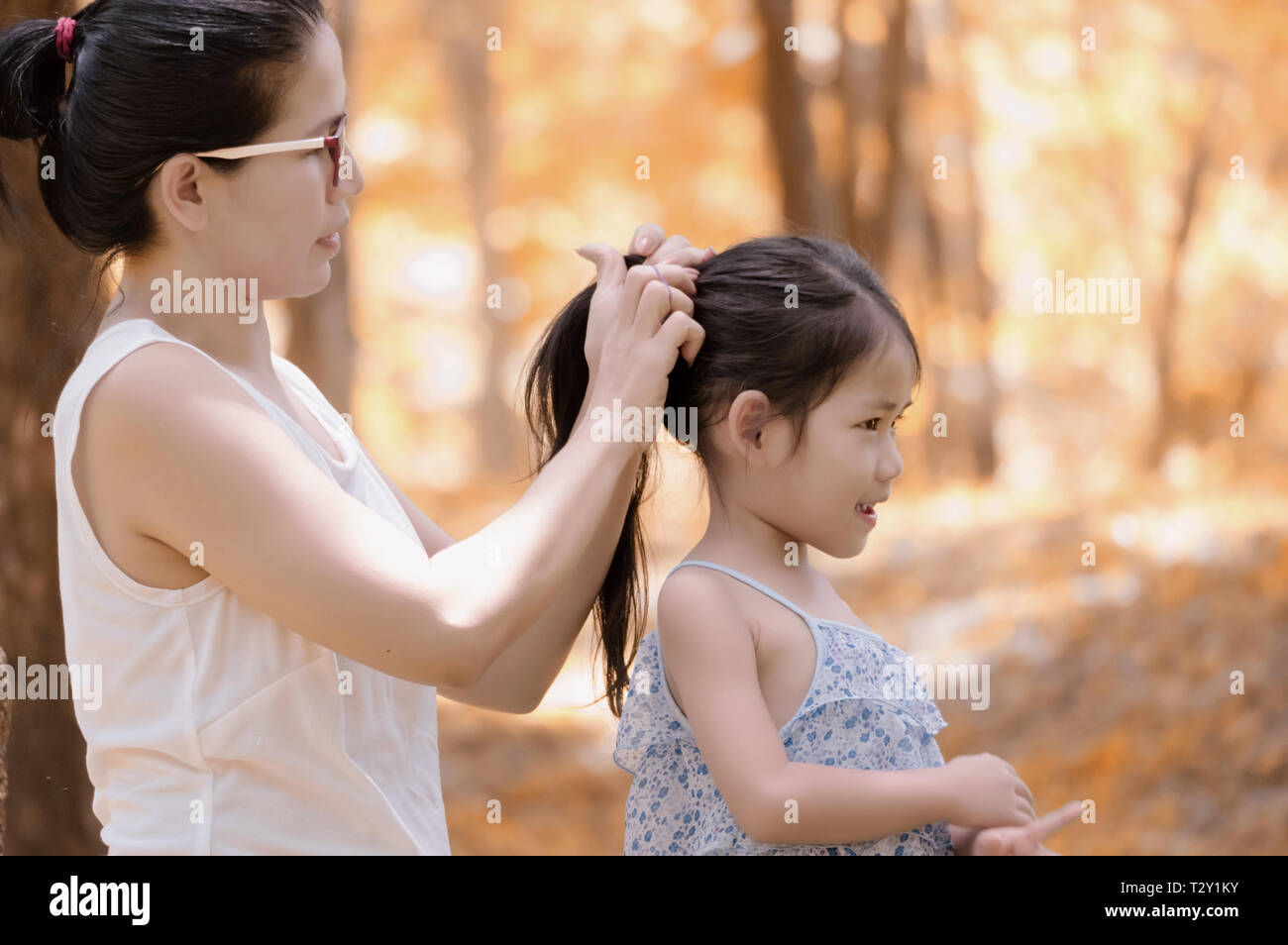 La madre è lo styling a sua figlia capelli all'aperto Foto Stock