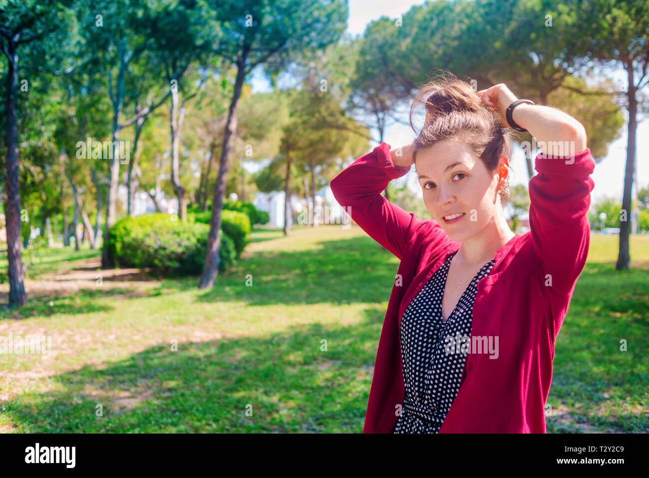 Bella giovane donna di vincolare il coda di cavallo all'aperto Foto Stock