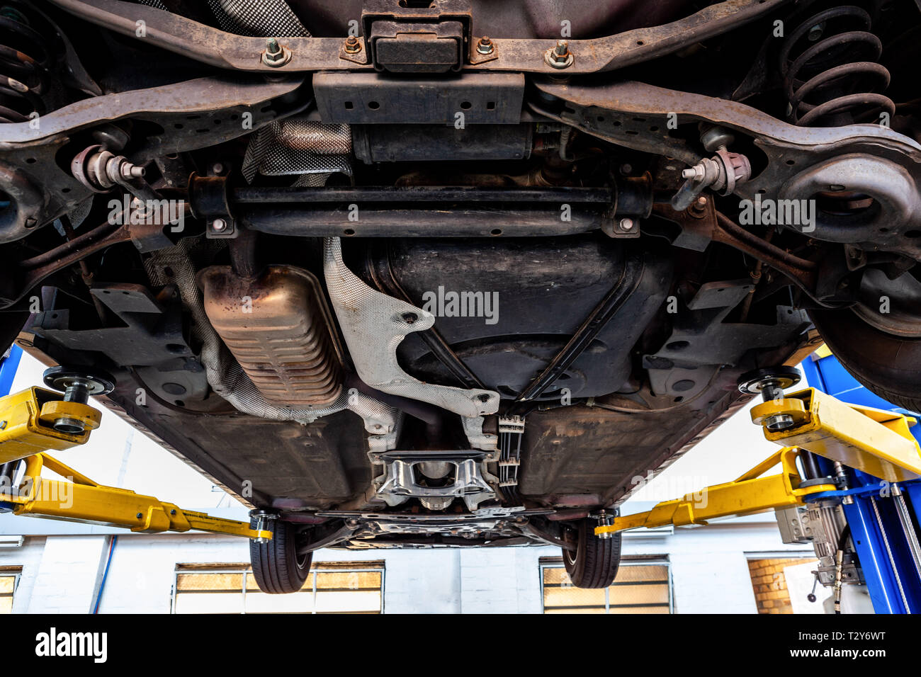 Vista del sottocarro per auto quando viene alzato il sollevatore idraulico in un workshop durante le procedure di ispezione Foto Stock
