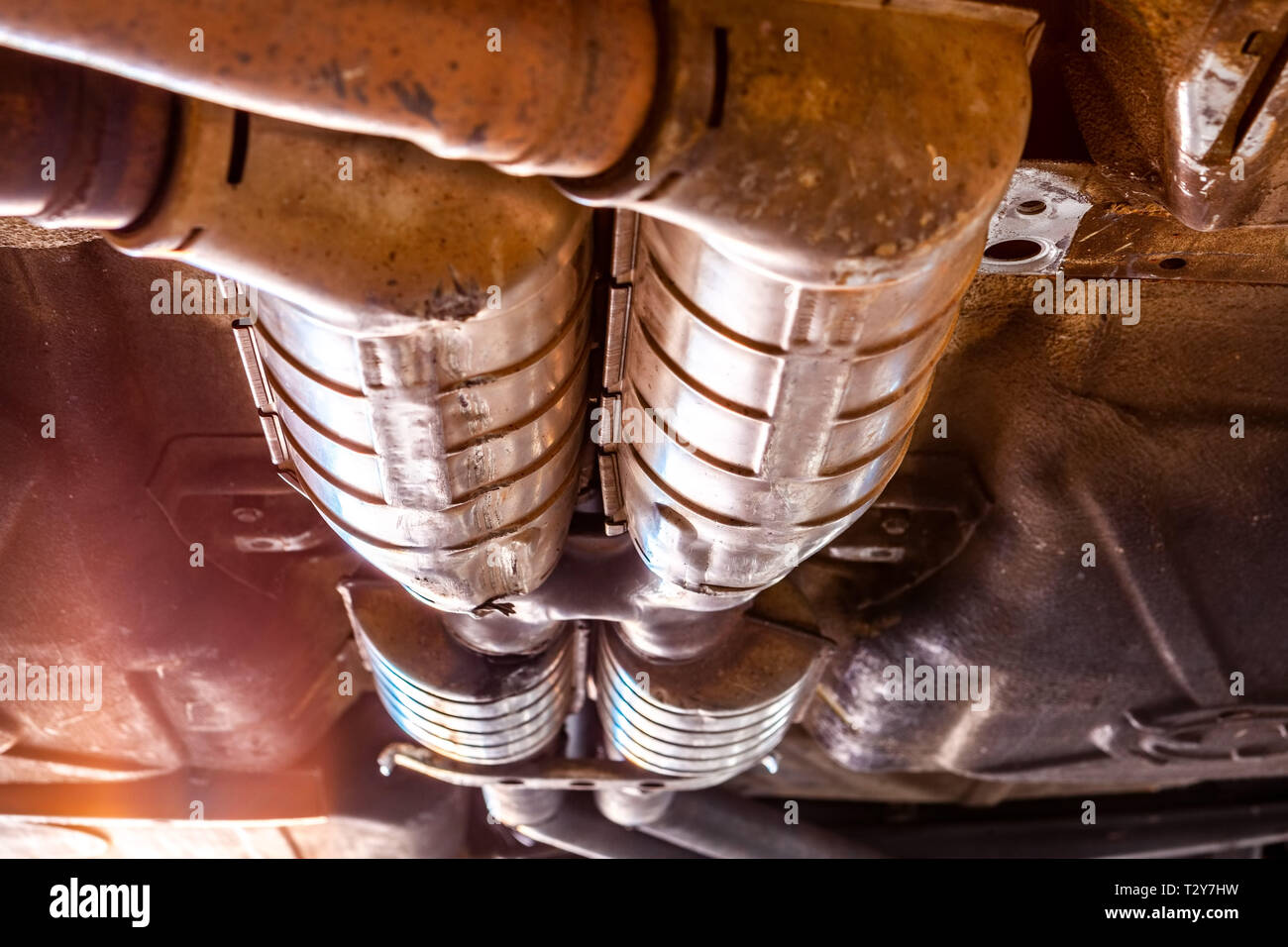 Extreme closeup di auto i tubi di scarico al di sotto del veicolo durante le riparazioni in officina Foto Stock