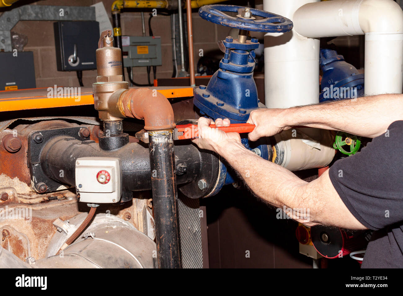 Ingegnere di caldaia servendosi di una chiave fissa per rimuovere un tubo  da una valvola di sicurezza su una vecchia caldaia a gas Foto stock - Alamy