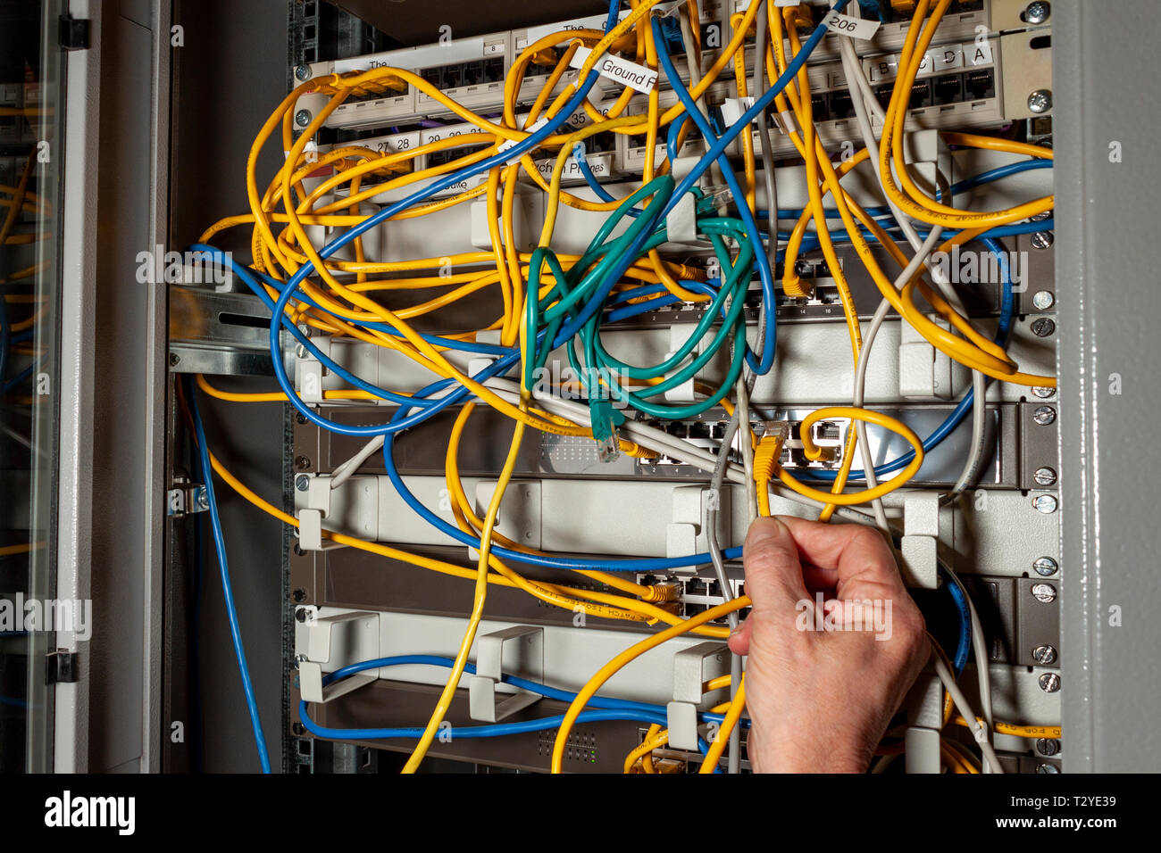 Ingegnere di reti di cavi di collegamento a uno switch di rete in un server di comunicazione mobile Foto Stock