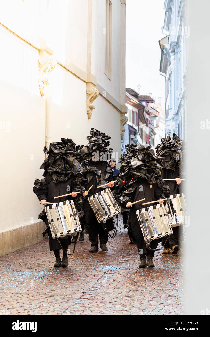 Rheinsprung Basel, Svizzera - Marzo 13th, 2019. Gruppo di percussionisti rullante in costume nero passeggiate nella città vecchia Foto Stock