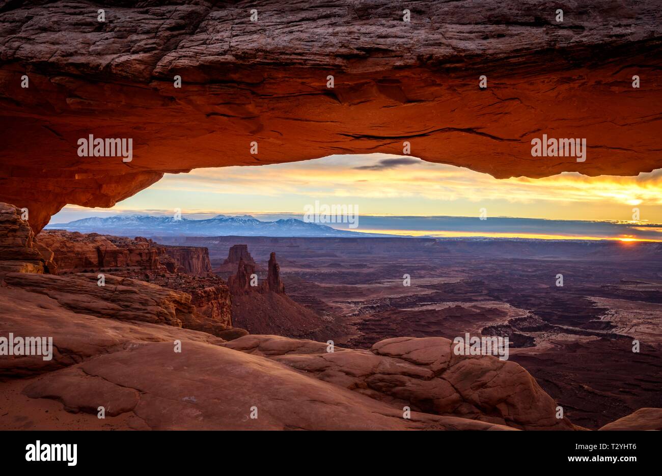 Vista attraverso arch Mesa Arch a sunrise, Colorado River Canyon con La Sal Mountains dietro, vista al Grand View Point Trail, Island in the Sky Foto Stock