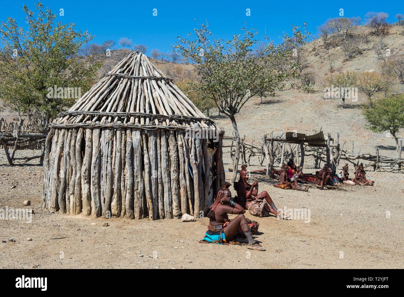 Le donne himba in un villaggio di capanne di legno, Kaokoland, Namibia Foto Stock Le donne himba in un villaggio di capanne di legno, Kaokoland, Namibia Foto Stock