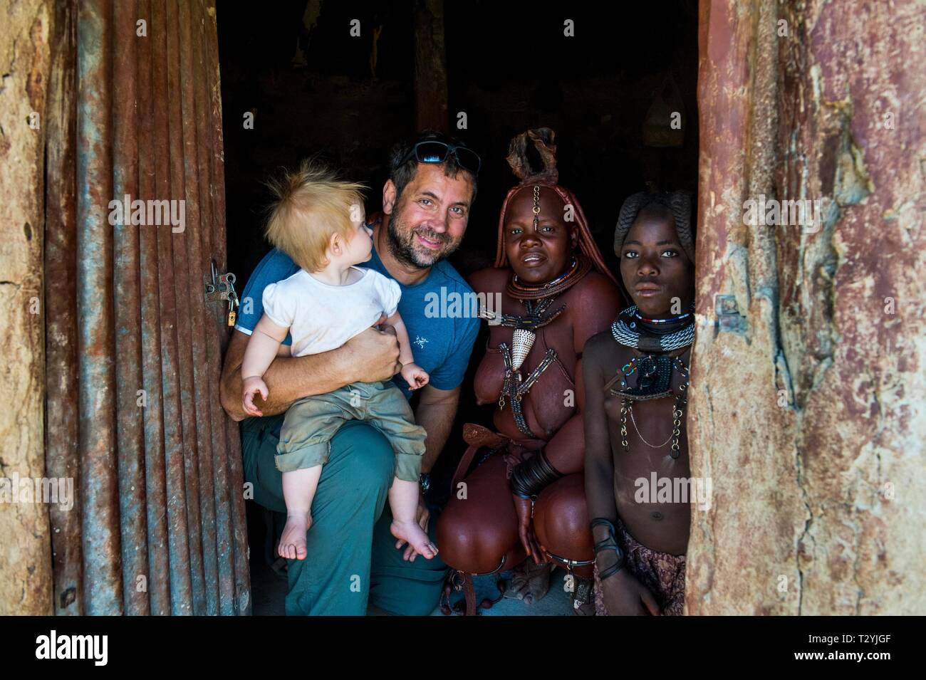 White turistico con il suo bambino in un villaggio Himba con il popolo Himba, Kaokoland, Namibia Foto Stock White turistico con il suo bambino in un villaggio Himba con il popolo Himba, Kaokoland, Namibia Foto Stock