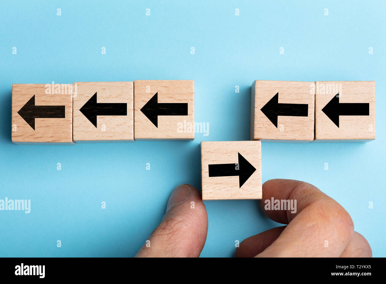 Una vista in alzata di mano d'uomo immissione segno di freccia blocco di legno con direzione opposta Foto Stock
