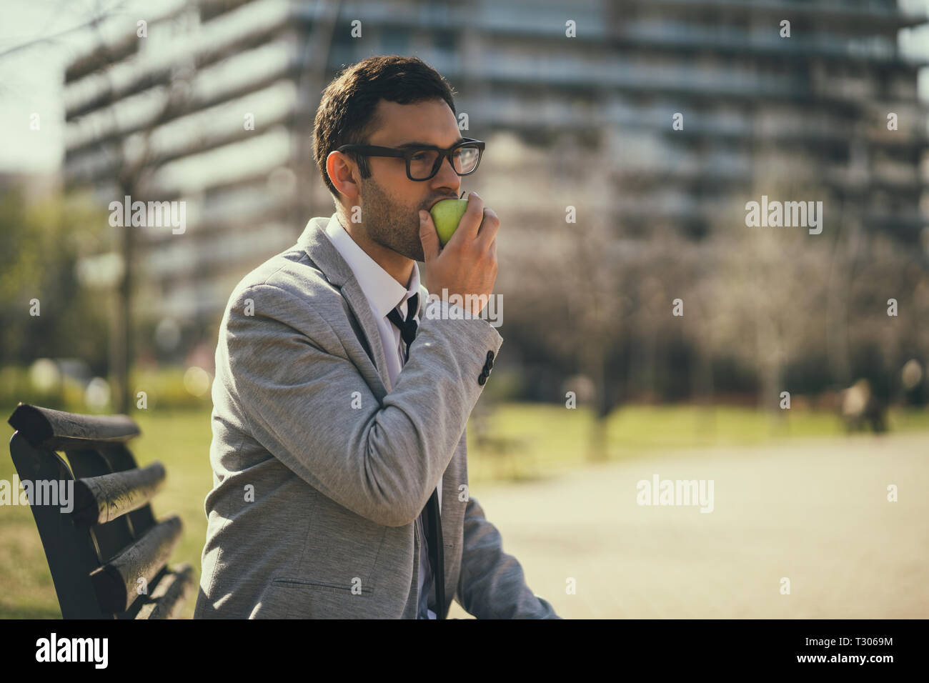 Giovane imprenditore è mangiare apple nel parco dopo il lavoro. Foto Stock
