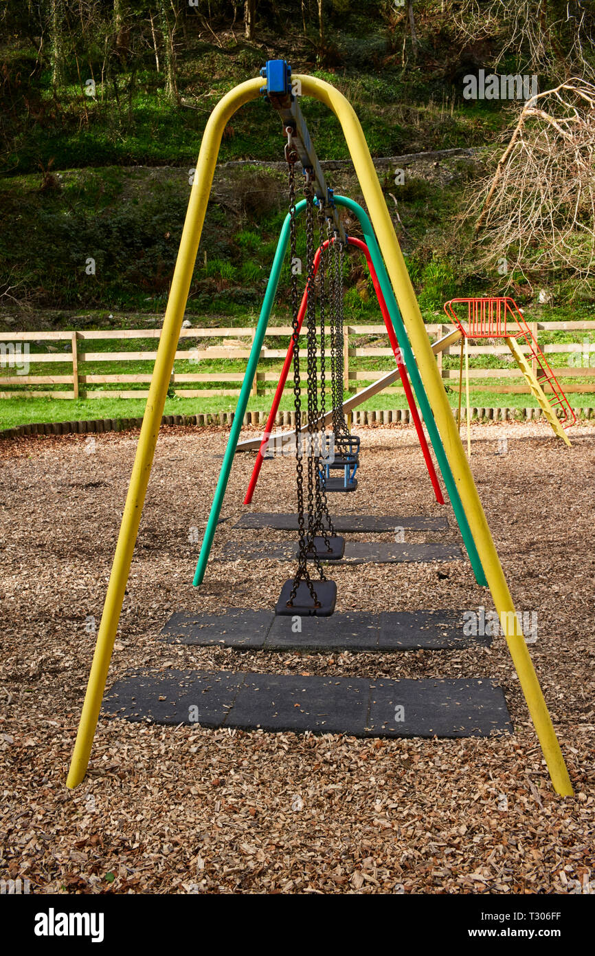 Vuoto un campo giochi per bambini con altalene impostato nel bosco in Laxey, Isola di Man Foto Stock