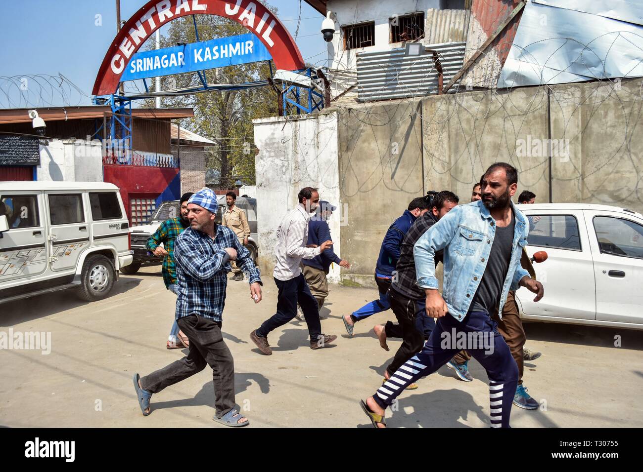 I parenti dei detenuti visto correre per coprire come forze di polizia inseguire il loro allontanamento al di fuori del carcere centrale durante la sommossa breakout a Srinagar Kashmir. Incidenti sono scoppiati all'interno di un alto grado di sicurezza centrale di prigione a Srinagar dopo le indiscrezioni di prigionieri che viene spostata al di fuori della valle del Kashmir. Nel frattempo le autorità hanno sospeso i servizi internet e imposto restrizioni nella vecchia città di Srinagar. Foto Stock