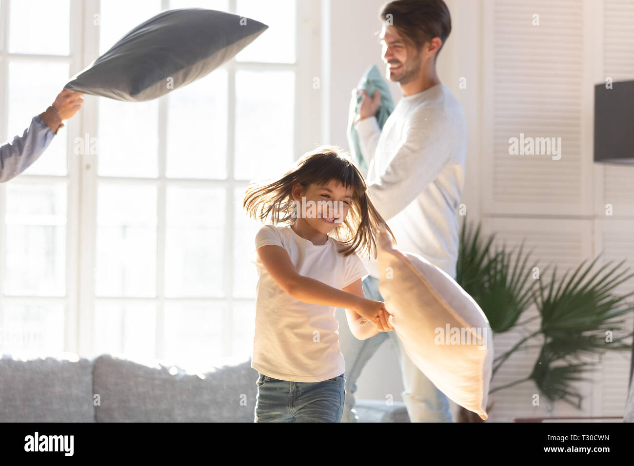 Famiglia allegra e piccola figlia gioca con cuscini a casa Foto Stock