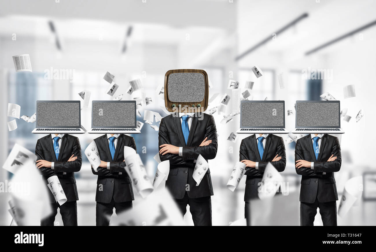 Uomini d'affari in giacca con i laptop invece dei loro capi mantenendo le braccia incrociate mentre sta in piedi in una riga e uno in testa con il vecchio televisore all'interno Ufficio BU Foto Stock