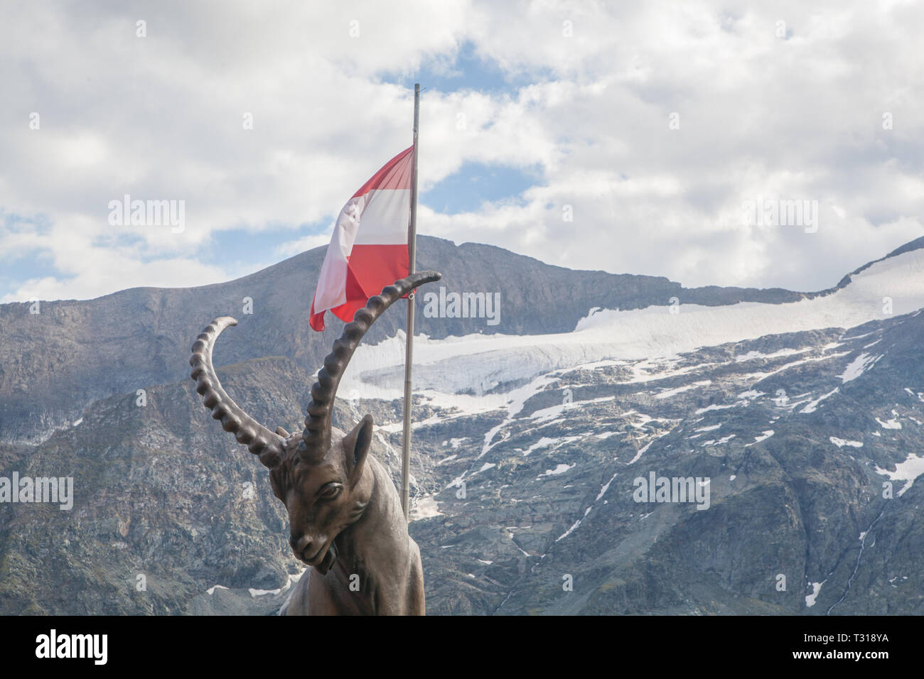Una statua del Capricorno con la bandiera austriaca e le montagne sullo sfondo Foto Stock