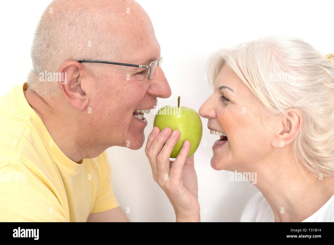 Coppia senior con mela verde. Denti sani, forte dentiere, nutrizione sana nozione Foto Stock