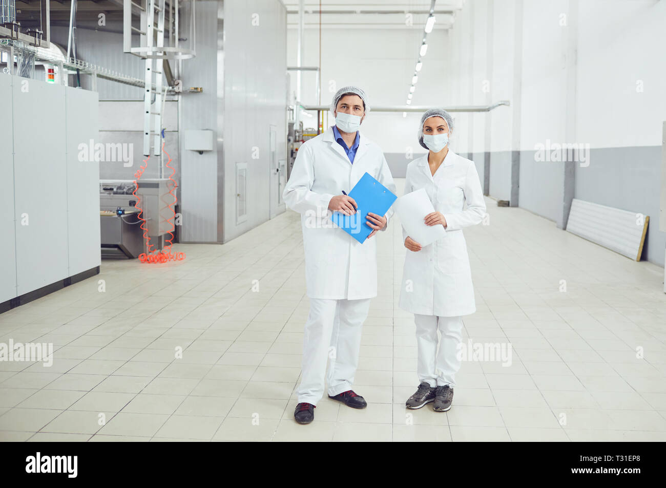 Persone tecnologi nelle maschere presso stabilimento alimentare. Foto Stock