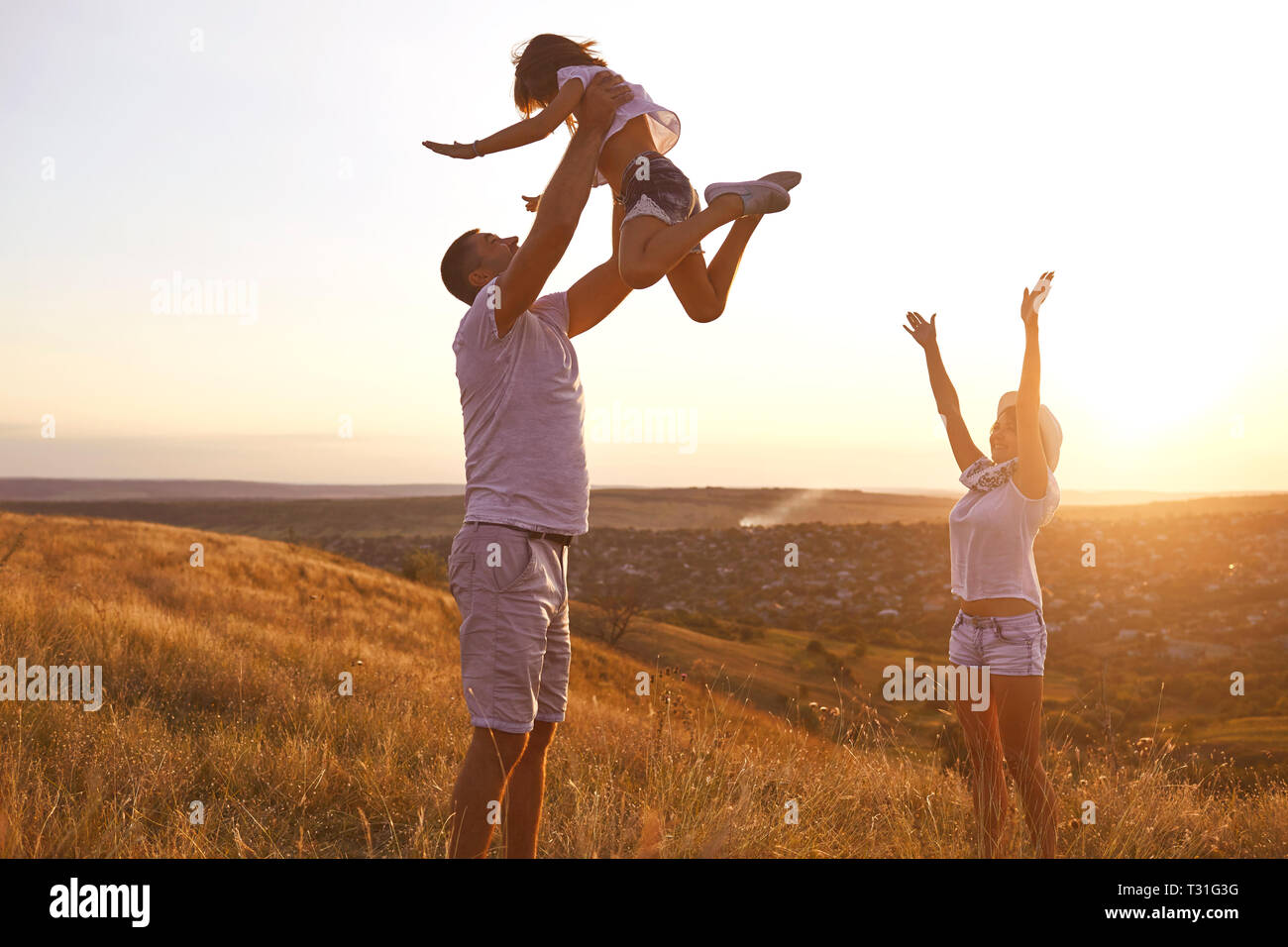La famiglia felice a piedi nella natura al tramonto in estate. Foto Stock