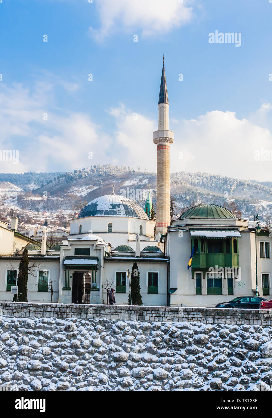 Un minareto sorge su edifici attraverso il fiume dalla città vecchia di Sarajevo. Gazi Husrev-bey moschea. La Bosnia Erzegovina Foto Stock