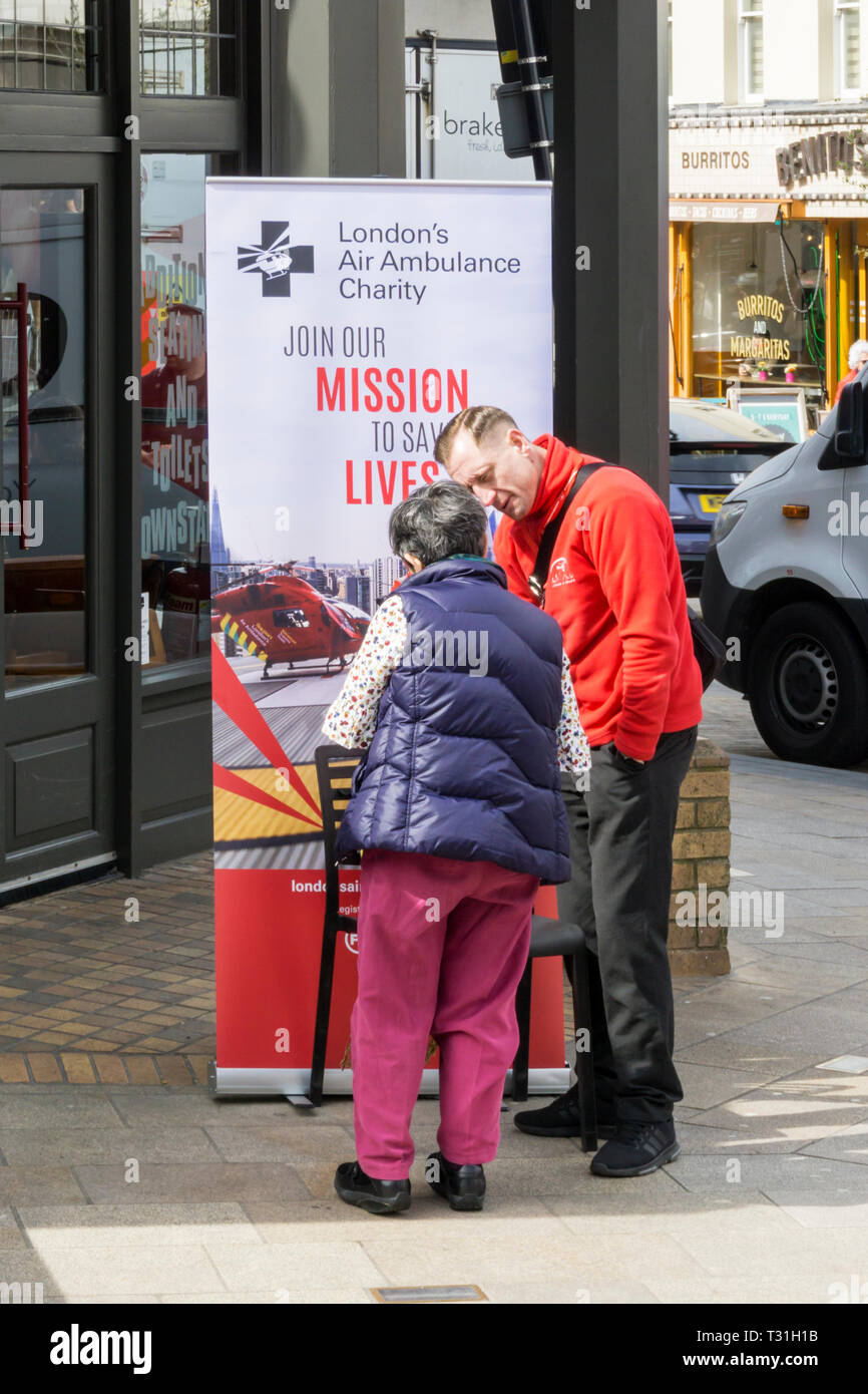 Un collettore di carità con un poster sollevando il supporto per London's air ambulance. Foto Stock